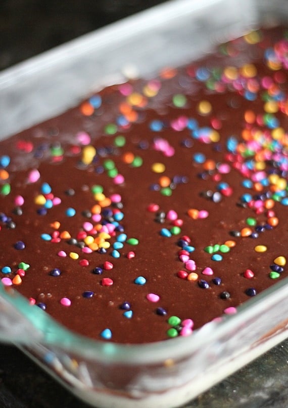 A glass baking pan of brownie batter with rainbow sprinkles on top