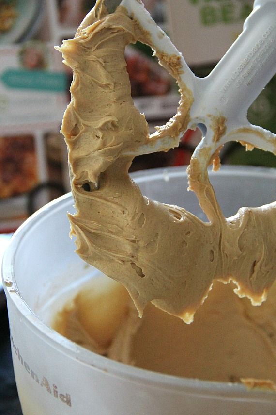 Peanut butter frosting mixture on the beater of a stand mixer