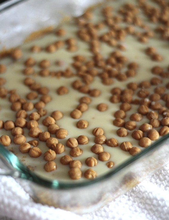 Caramel bits on top of sweetened condensed milk and graham cracker crumbs in a baking dish