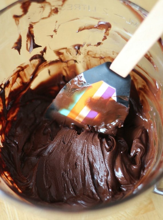 Melted chocolate and butter mixture in a bowl with a spatula