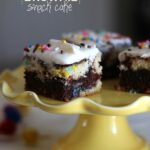 Squares of cake batter brownie snack cake on a yellow cake stand