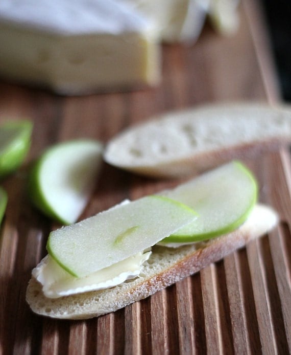 A slice of bread with sliced Brie and Granny Smith apple on top
