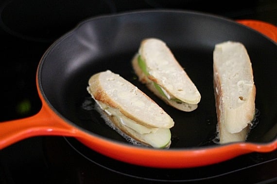 Three Apple and Brie Grilled Cheese Sandwiches cooking in a skillet