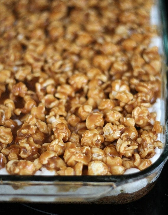 Peanut butter popcorn over marshmallow and cookie layers in a baking pan