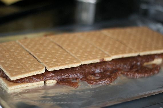 A line of graham cracker sandwiches filled with melted chocolate mixture