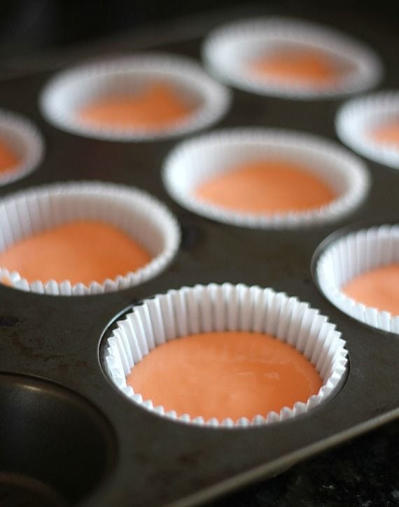 Paper-lined muffin cups filled with orange jello yogurt mixture