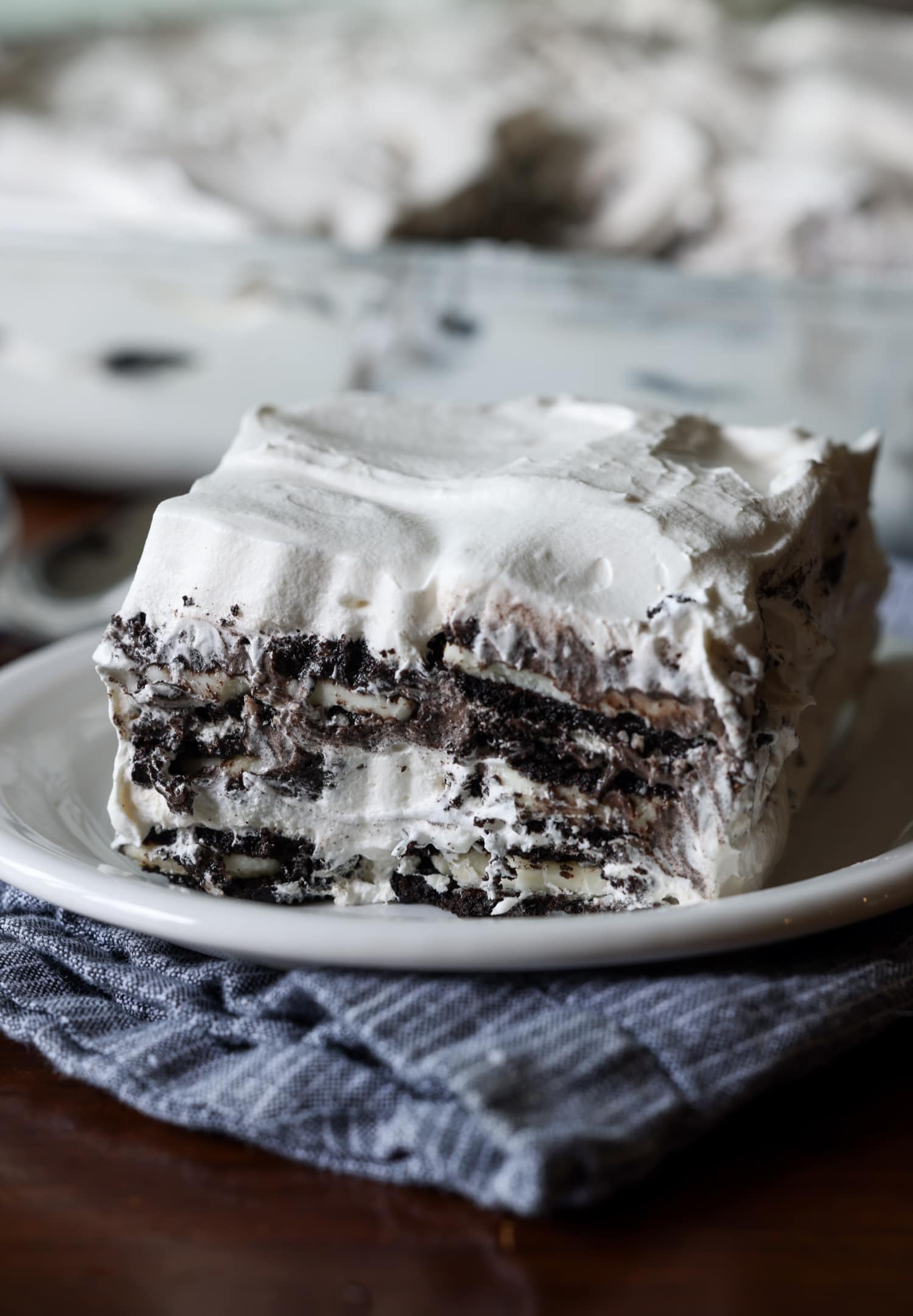 Oreo Icebox Cake sliced on a white plate topped with cool whip