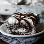 A slice of Oreo Icebox Cake on a white plate topped with hot fudge sauce