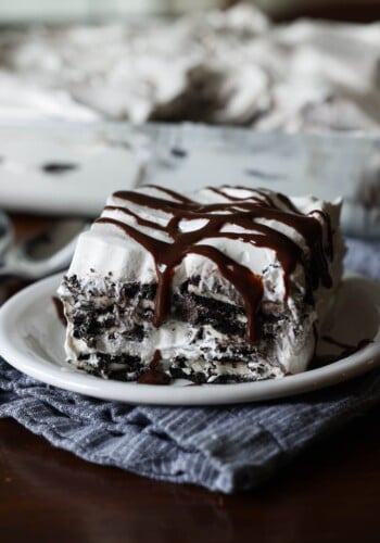 A slice of Oreo Icebox Cake on a white plate topped with hot fudge sauce
