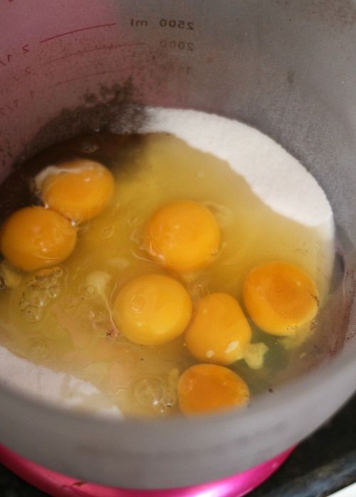 Seven eggs over cocoa powder and sugar in a mixing bowl