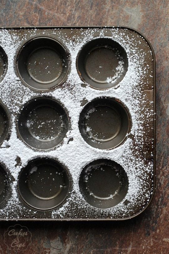 Empty muffin tin with powdered sugar around the muffin cups