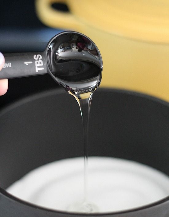 A tablespoon of corn syrup being added to a saucepan