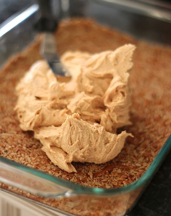 Peanut butter filling being spread over pretzel crust in a pan