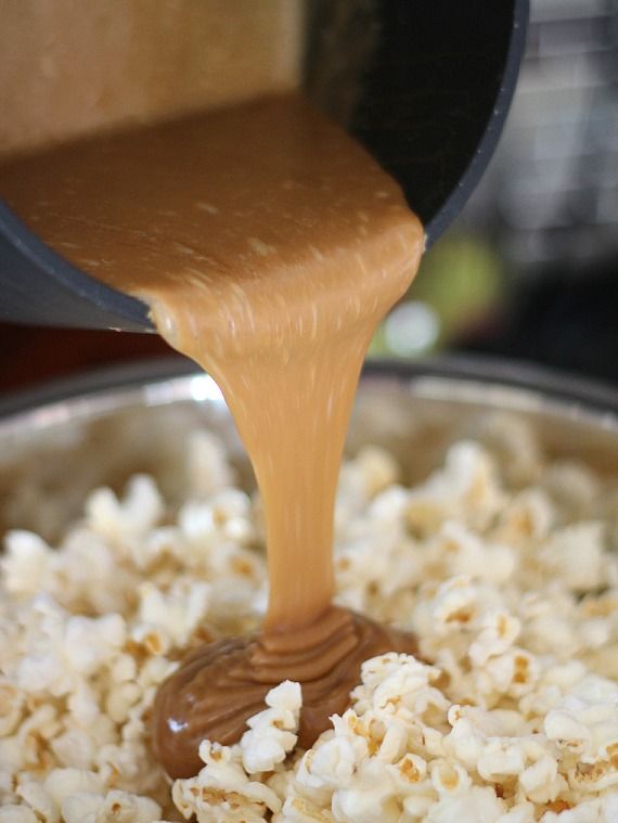 Peanut butter caramel sauce being poured over a bowl of popcorn