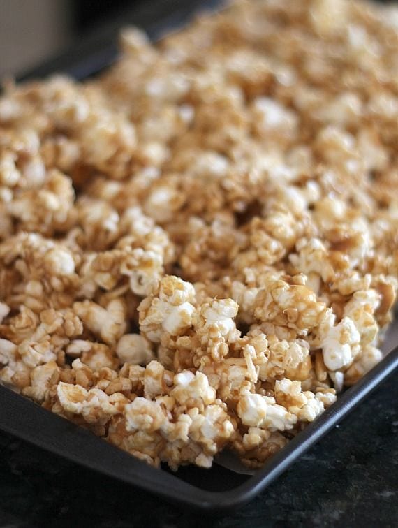 Peanut butter caramel krispie popcorn spread on a baking sheet