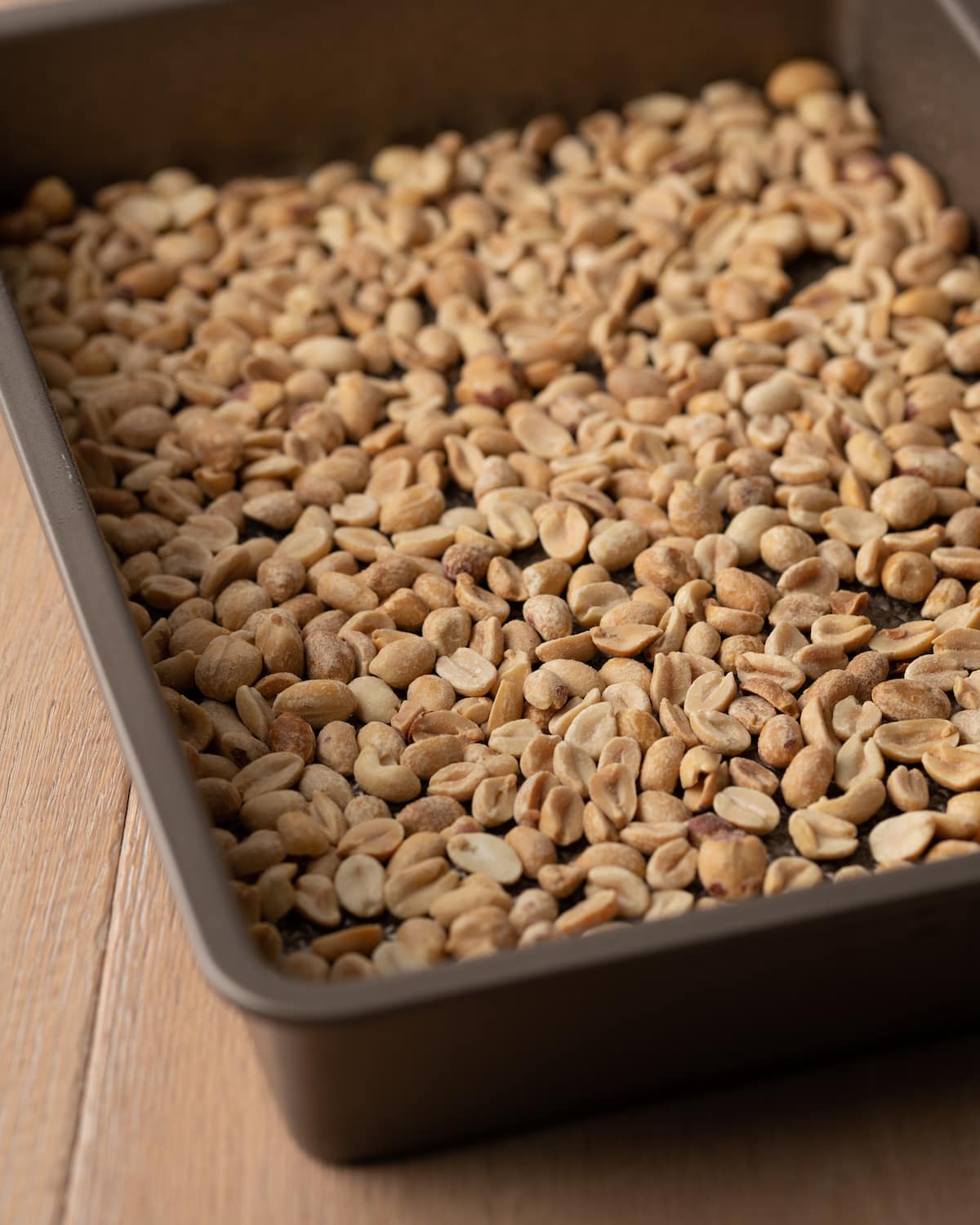 Peanuts laid in the bottom of a baking pan.