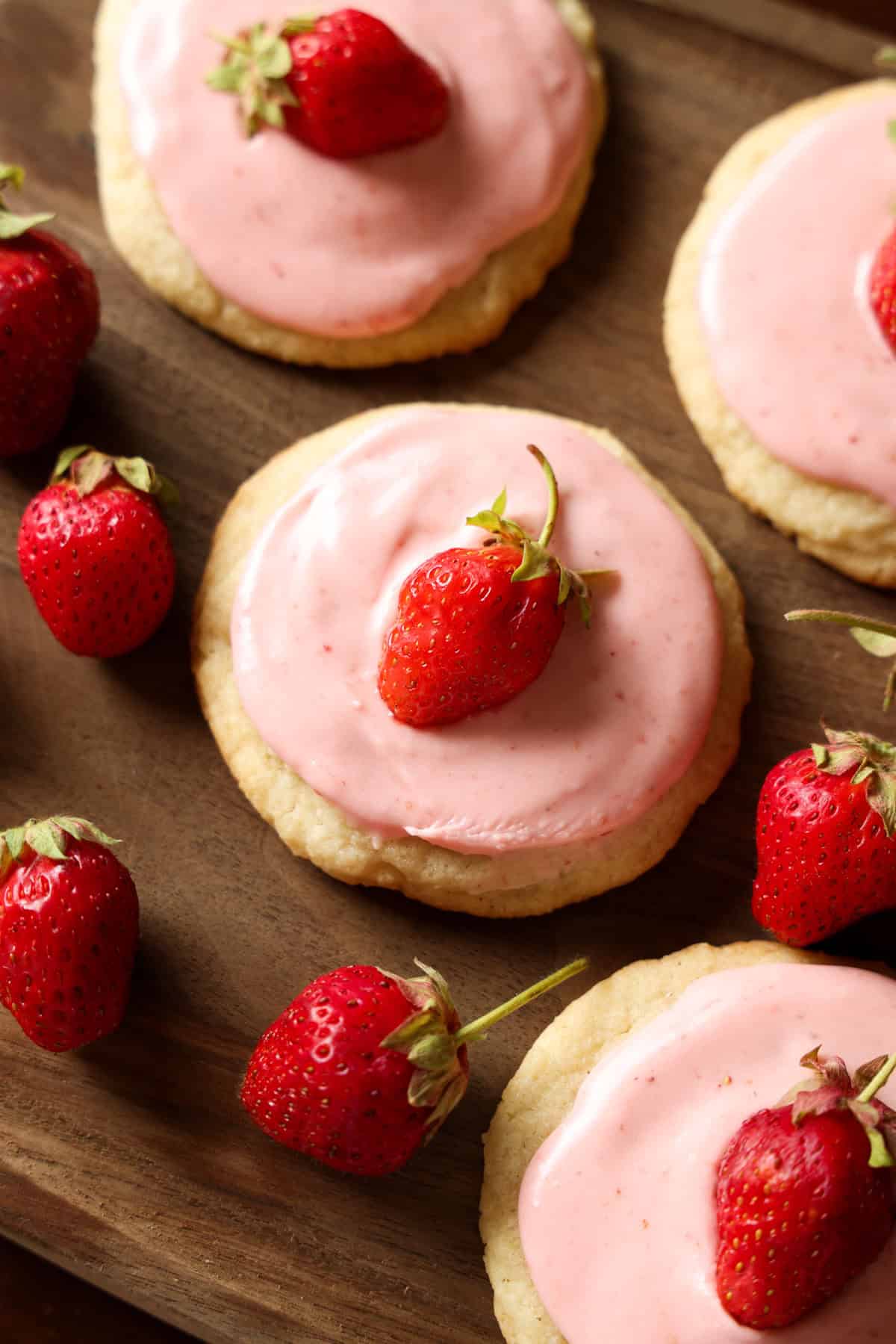 Strawberry cookies topped with pink strawberry frosting and a fresh strawberry