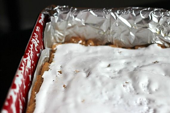 Marshmallow fluff spread over peanut butter blondies in a pan