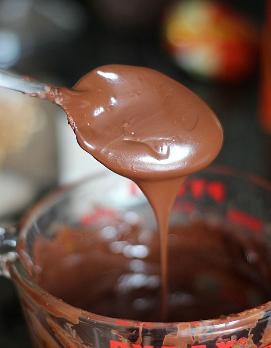 A spoonful of melted chocolate over a liquid measuring cup of melted chocolate