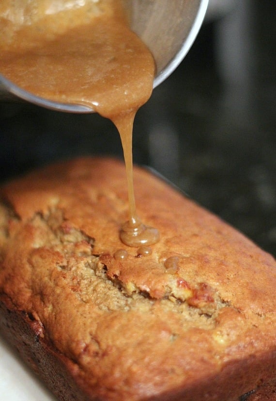 Brown butter glaze being poured over a loaf of banana bread