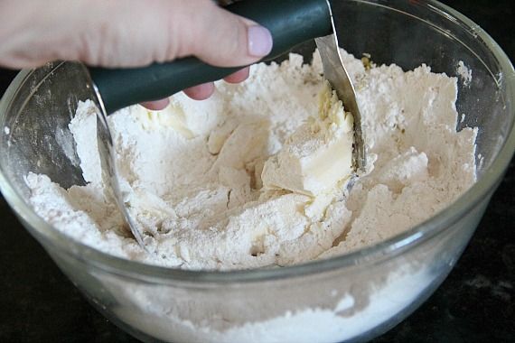 A pastry cutter combining butter and dry ingredients in a mixing bowl