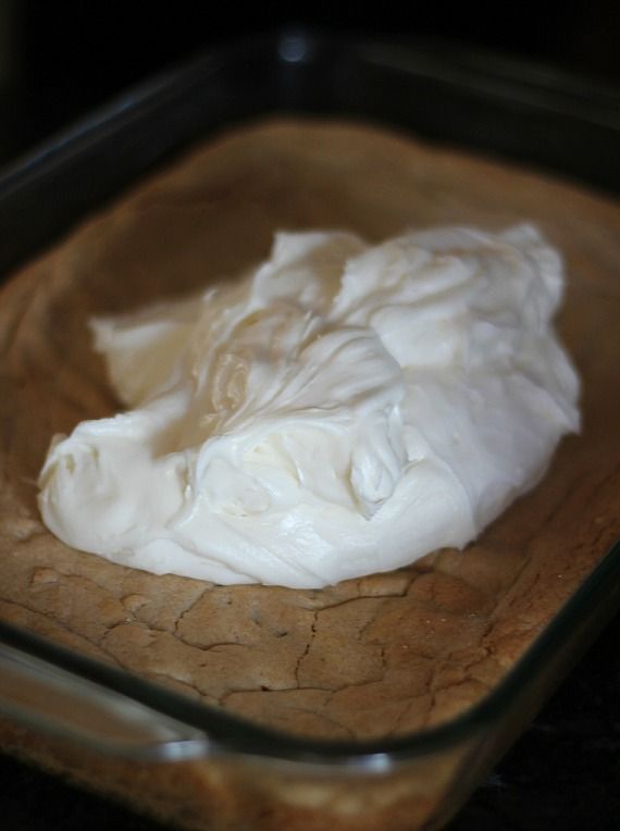 Cream cheese frosting on top of a pan of cinnamon roll cookie bars