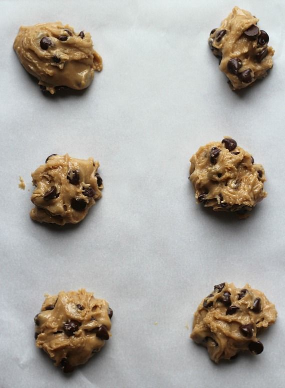 Chocolate chip cookie dough globs on a parchment-lined baking sheet