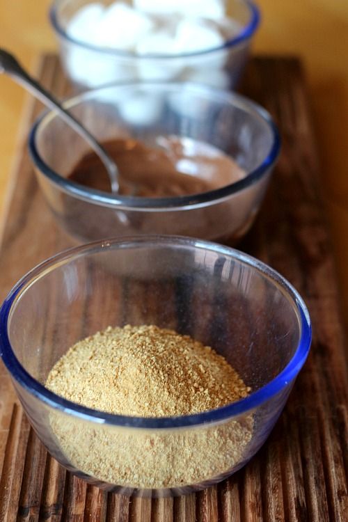 Bowls of marshmallows, melted chocolate, and graham cracker crumbs