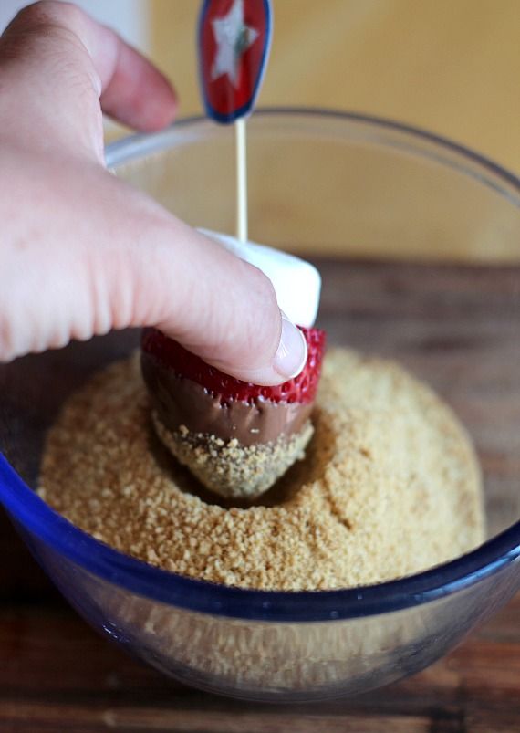 Chocolate-dipped strawberry and marshmallow being dipped in graham cracker crumbs