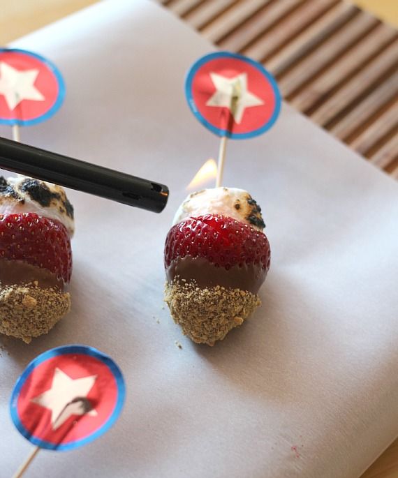 Strawberry S'mores skewers with toasted marshmallows on parchment paper