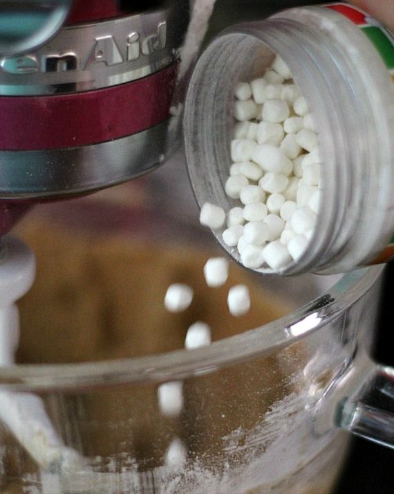 Marshmallow bits being poured into a stand mixer bowl
