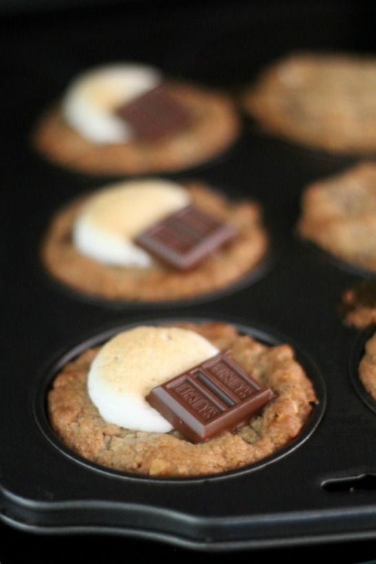 Deep dish smores cookies in a muffin top pan topped with marshmallow and chocolate pieces