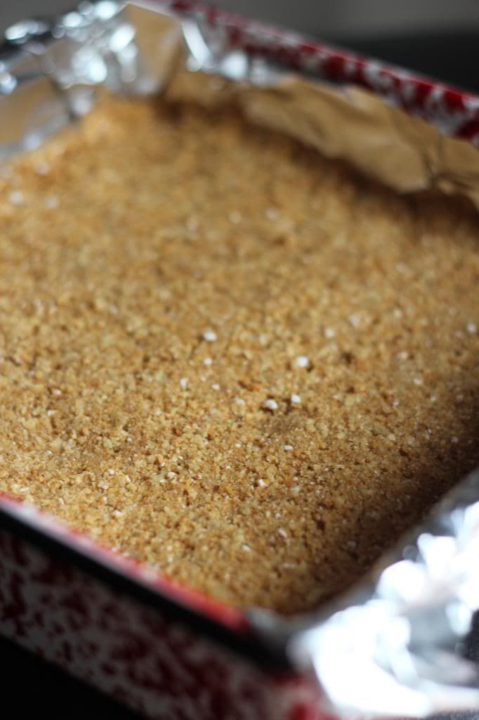 Graham cracker crumbs spread in a foil-lined square pan