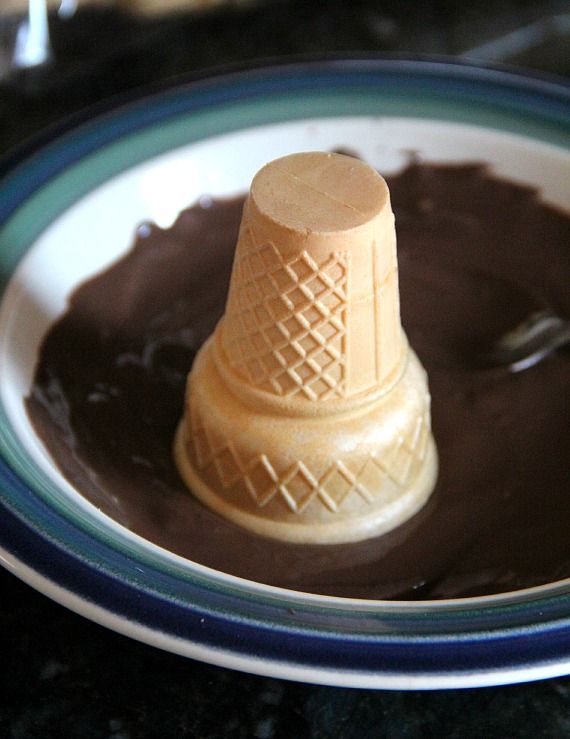 Ice cream cone upside down in a shallow plate of melted chocolate