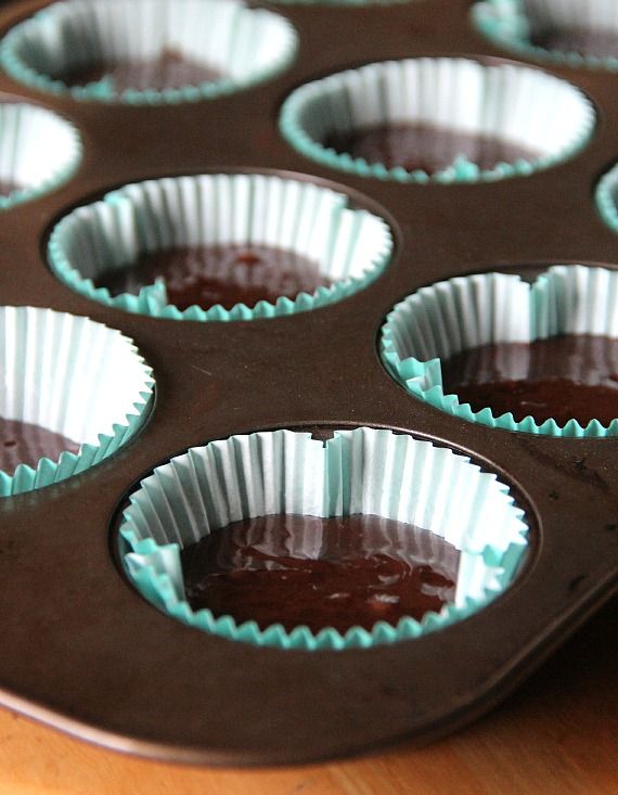 Paper muffin cups filled with chocolate batter in a muffin tin