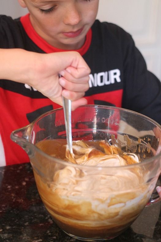 A little boy stirring a bowl of root beer batter
