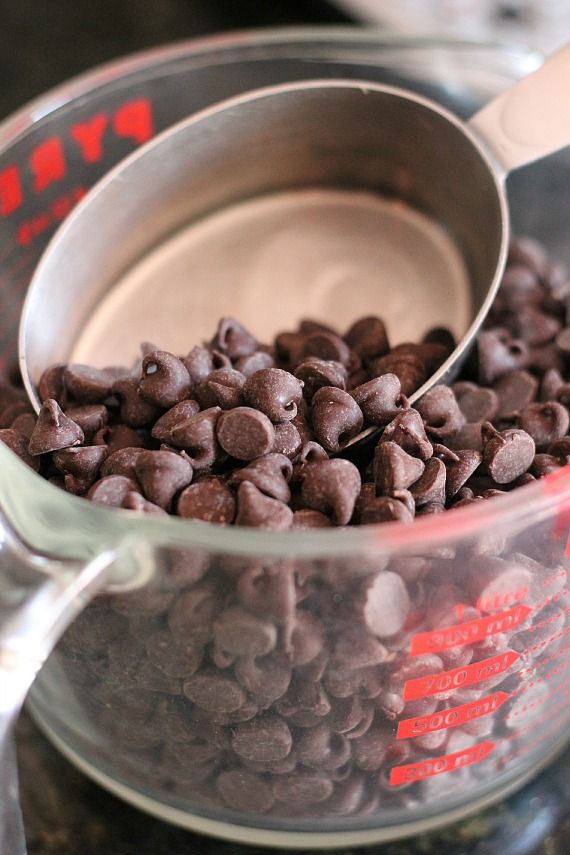 Chocolate chips in a glass measuring cup with a scoop