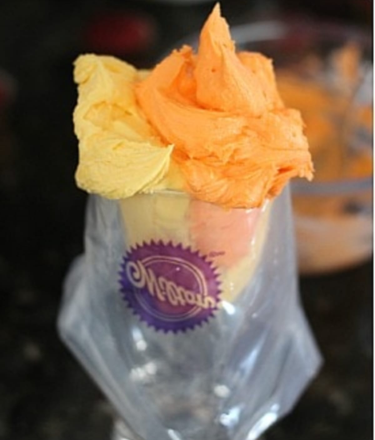 Filling a piping bag with orange and yellow frosting