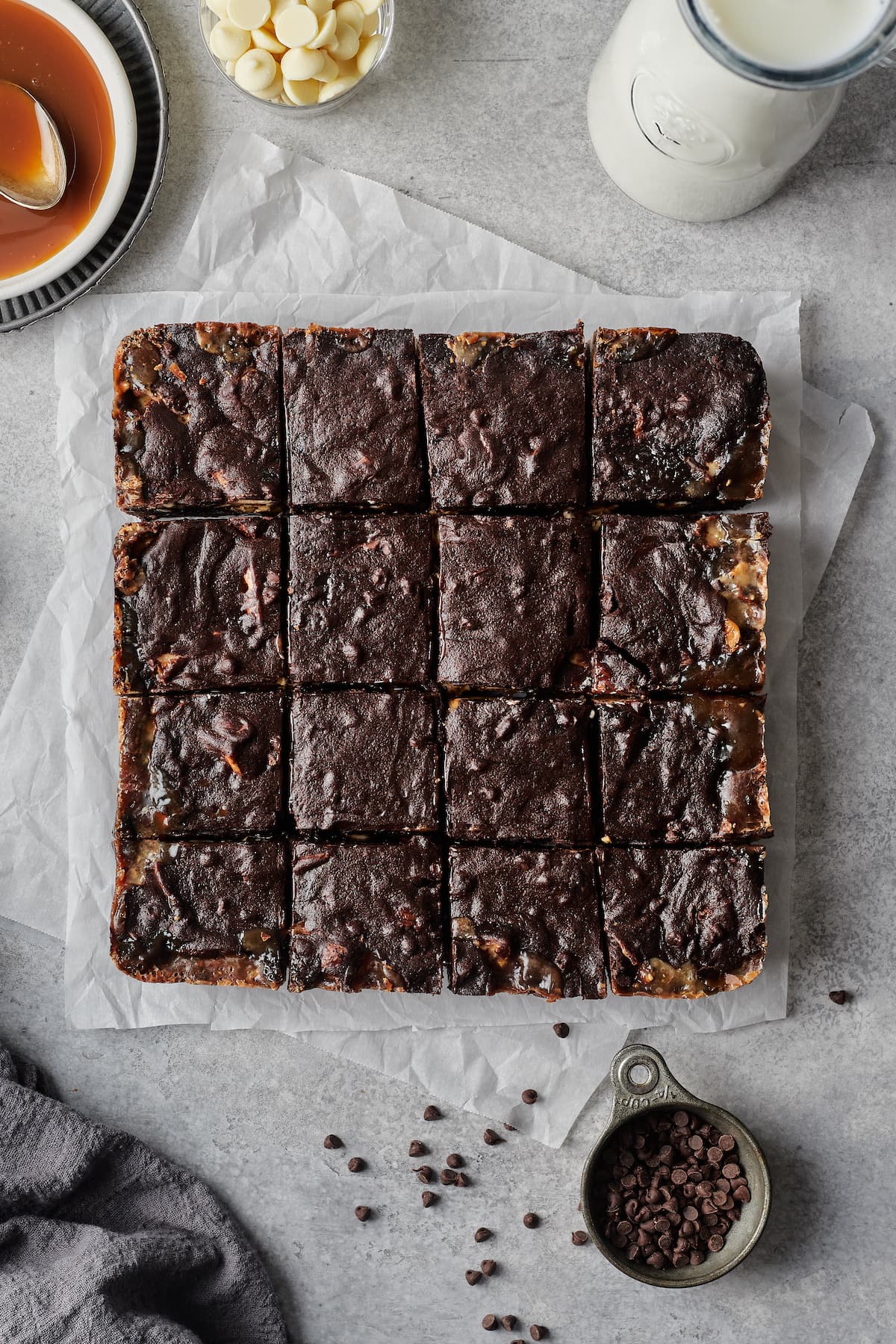 Baked brownies on parchment paper, sliced into squares.