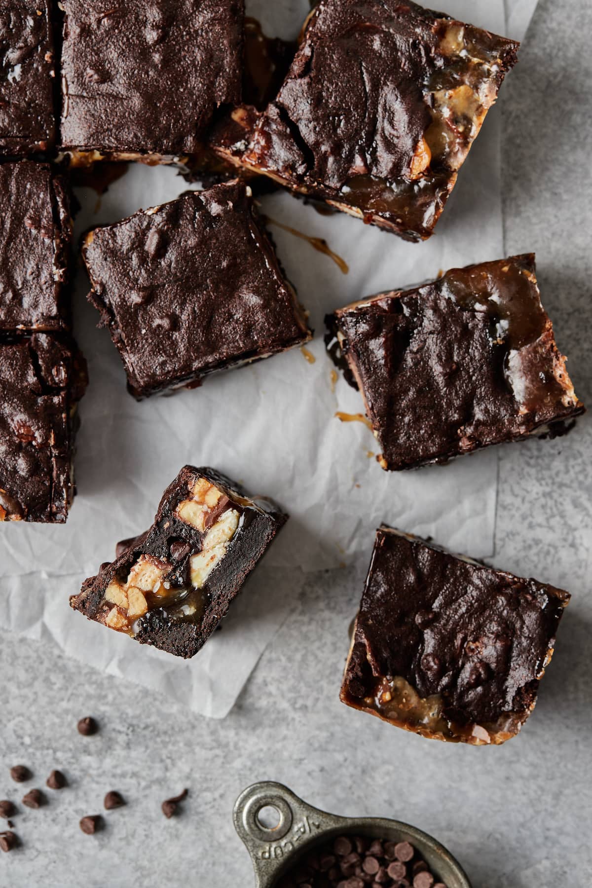 Snickers brownies scattered on parchment paper.