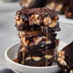 A stack of gooey chocolatey Holy Heck Snickers brownies.