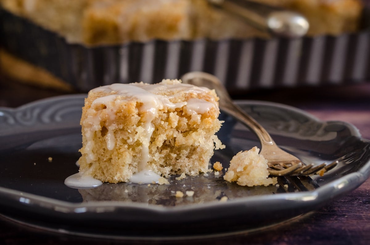 A slice of iced banana crumb cake with a bite taken out