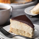 A slice of Boston Cream Pie cheesecake on a plate next to a fork.