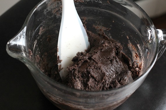 A white spoon is used to stir cake mix brownie batter in a mixing bowl.