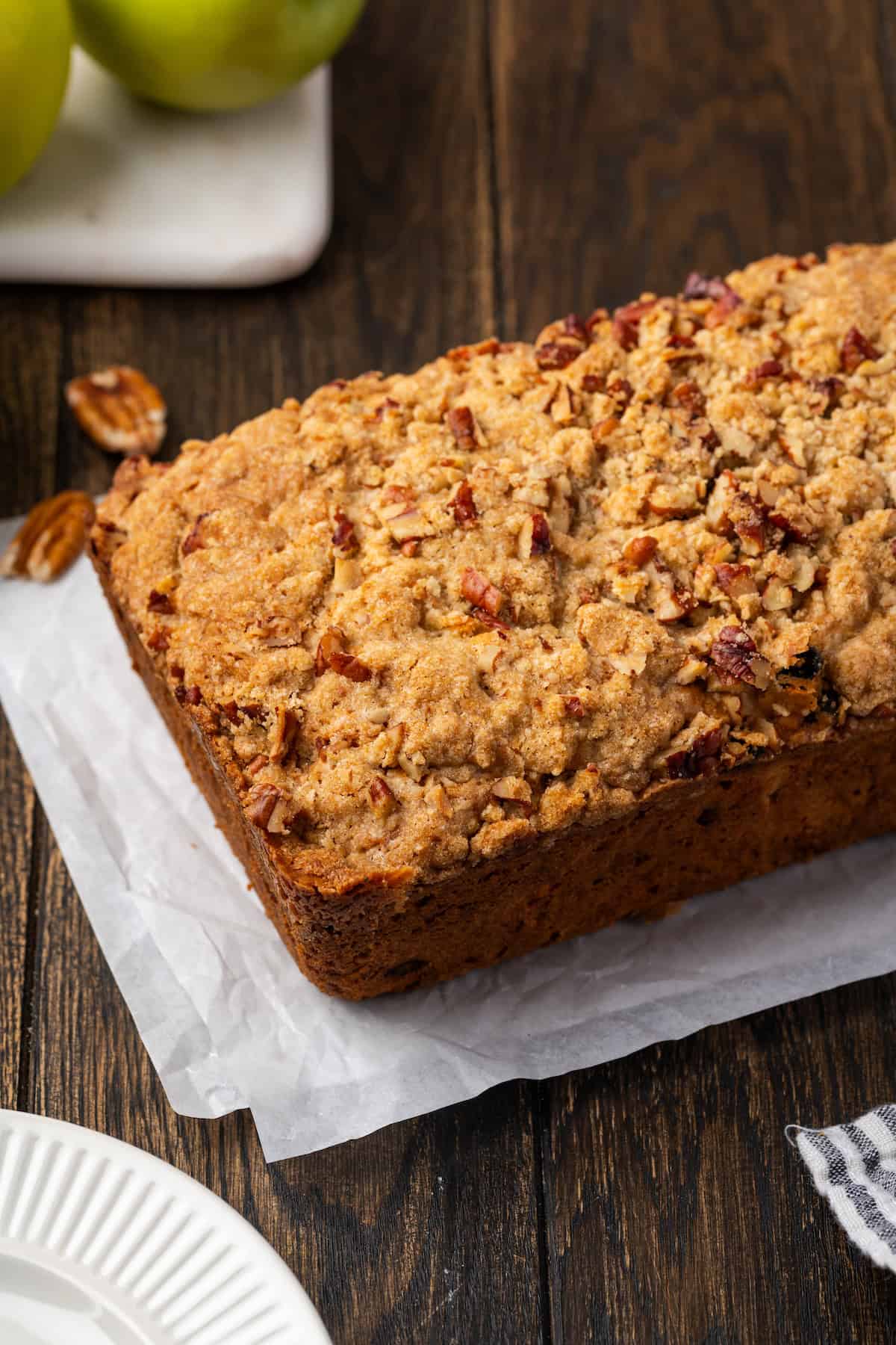 A loaf of apple pie bread on a sheet of parchment paper.