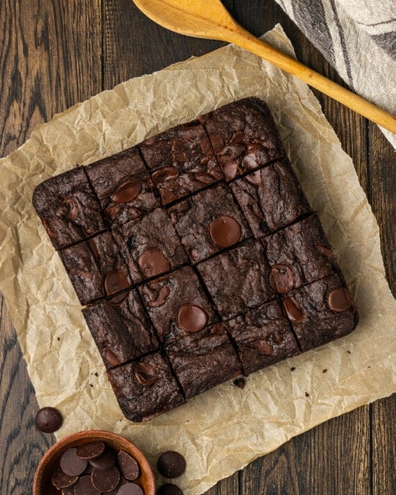 Overhead view of cake mix brownies cut into squares on a sheet of parchment paper.