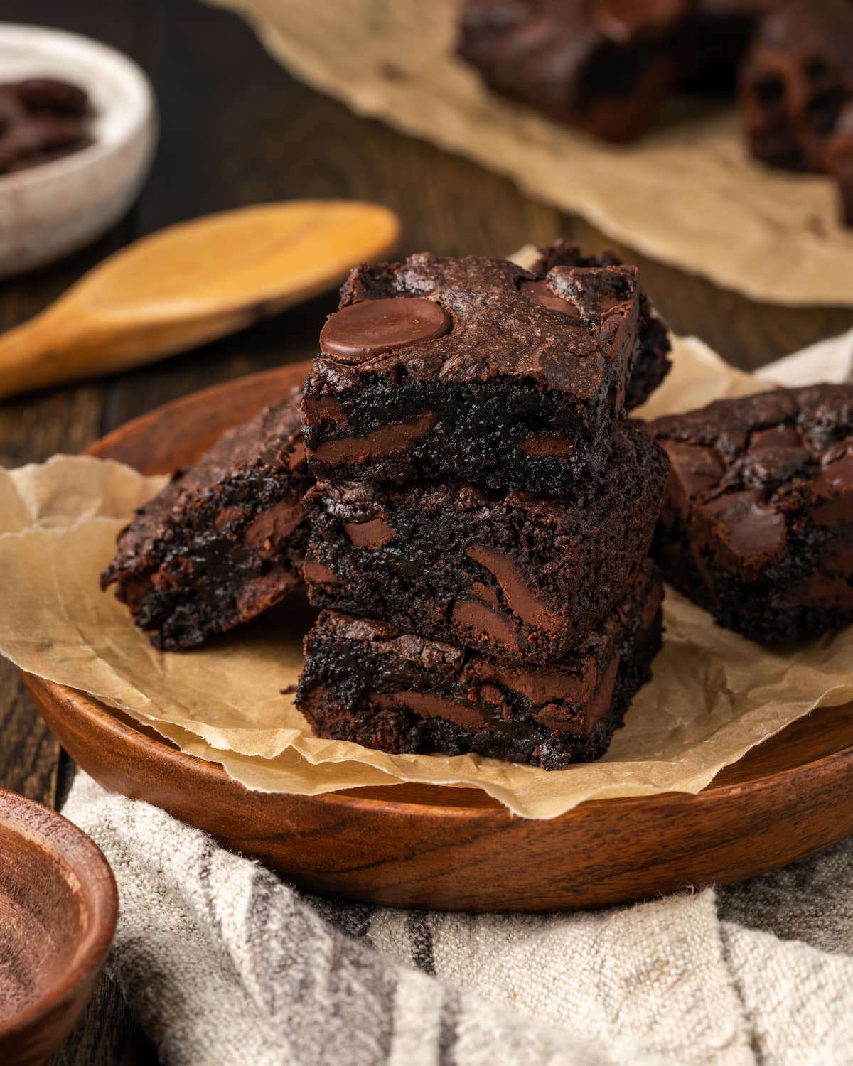 A stack of fudgy cake mix brownies on a plate lined with parchment paper.