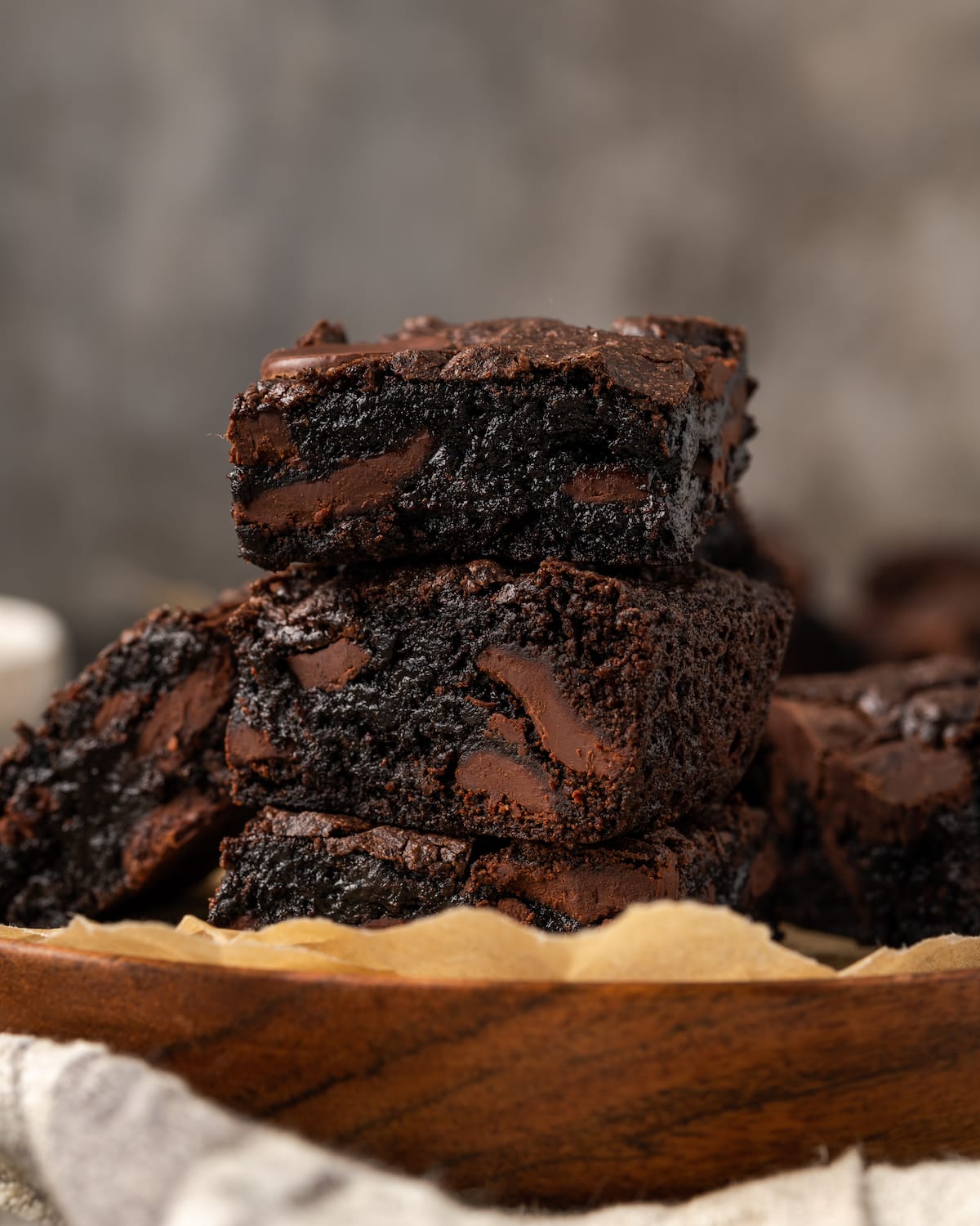 A stack of fuzzy cake mix brownies on a plate lined with parchment paper.