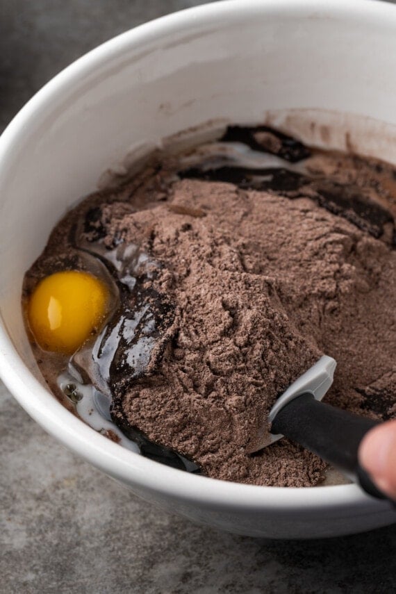 Cake mix brownie ingredients are stirred together in a large bowl.