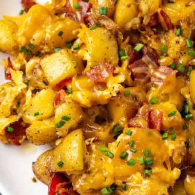 Close up of cheesy ranch potatoes on a white platter.